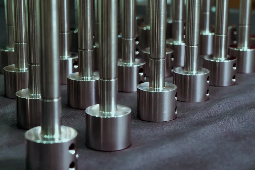 High-volume batch CNC precision turned stainless steel stepped shaft components with mirror polished shafts and drilled cylindrical bases — custom high-volume stainless steel CNC turning for industrial and OEM manufacturing