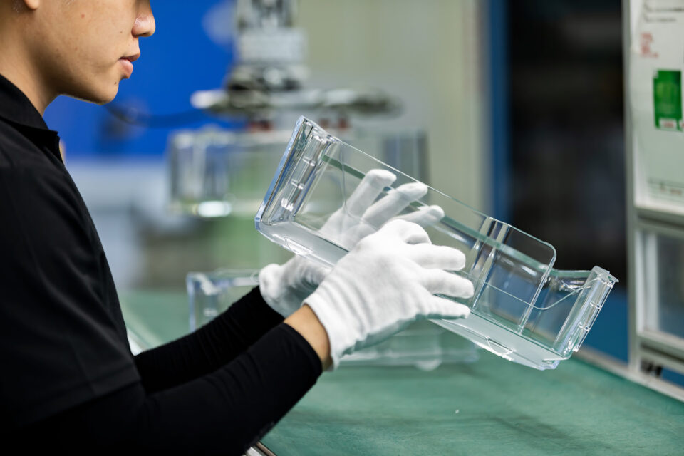 White-glove QC inspection of transparent PC PMMA injection molded thin-wall enclosure housing — precision injection mold manufacturing with controlled uniform wall thickness structural integrity and optical grade surface finish for consumer electronics and medical device applications