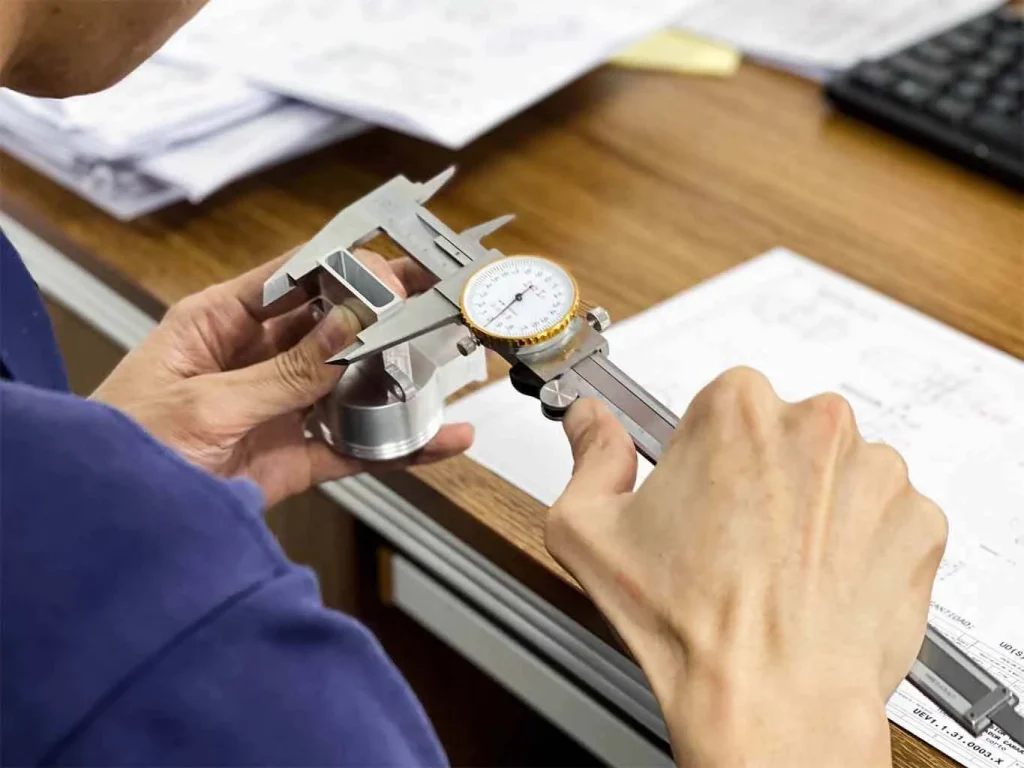 Strict CNC machining quality control and dimensional inspection of custom aluminum parts using high-precision dial calipers for tight tolerance industrial manufacturing