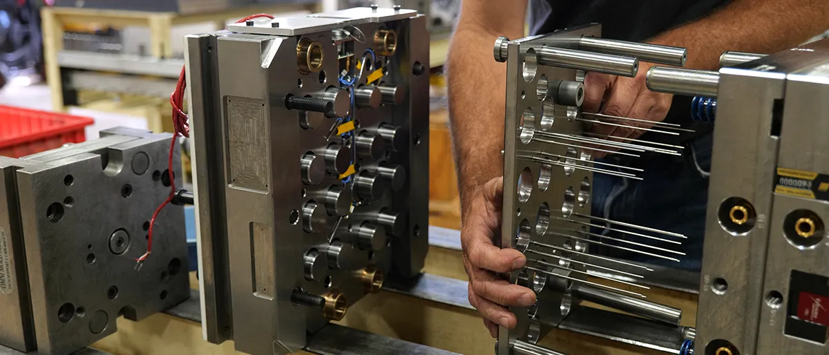 Professional injection mold manufacturer assembling precision multi-cavity plastic injection mold with hot runner system, ejector pins, guide pillars, and custom tooling components for prototype tooling, production molds, and high-volume injection molding manufacturing.