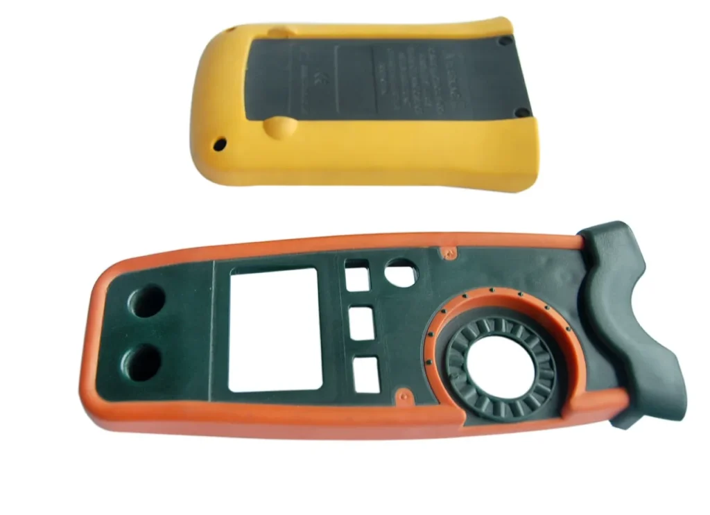 Two-shot overmolded injection mold plastic housing for handheld electronic instrument with display cutout and rotary dial — custom consumer electronics enclosure mold manufacturing